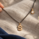 Colgante de inicial con detalle de luz. El motivo principal dibuja una letra S de superficie lisa.